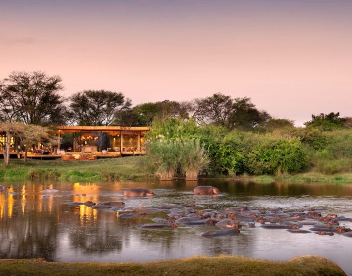 Tanzania-Grumeti-Serengeti-River-Lodge-Guest-Area-exterior-view-with-hippo-pod-in-rive